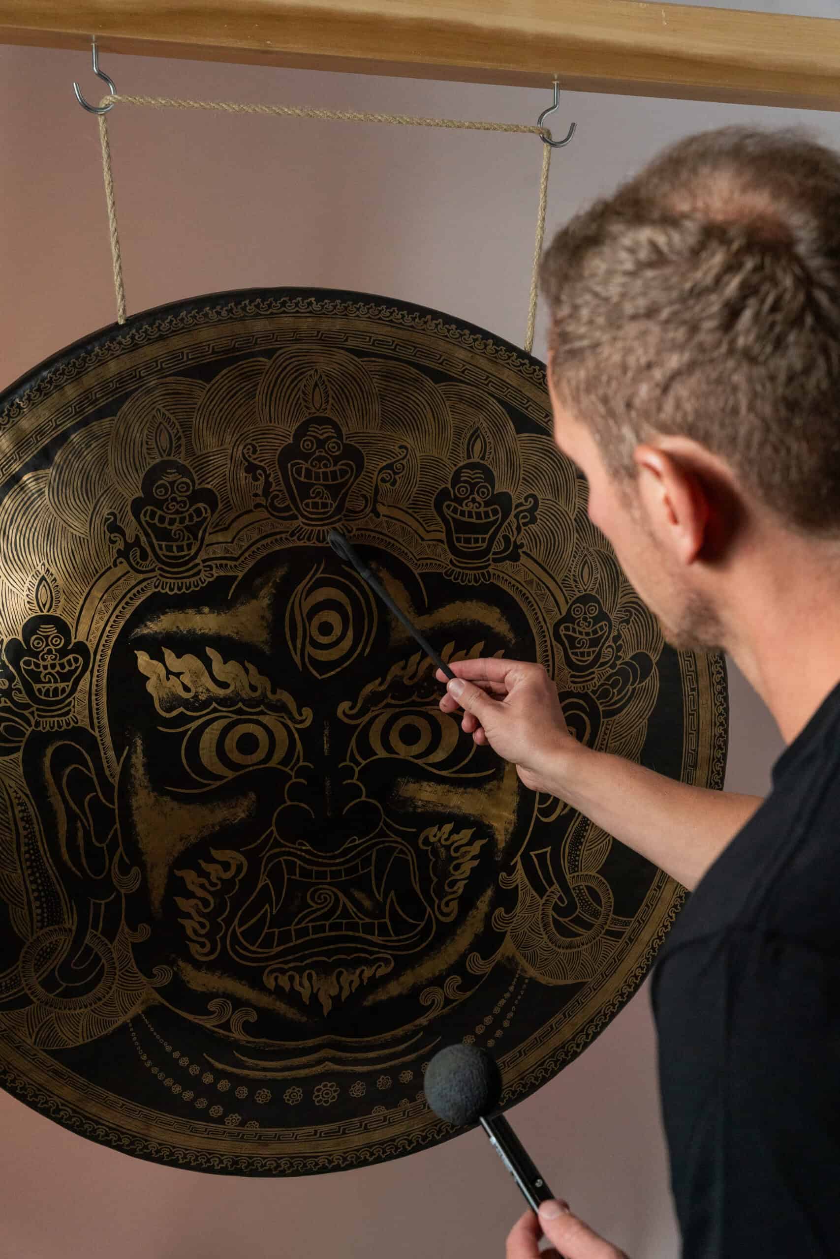 Jens Kemna playing a large gong during a sound bath for teams session